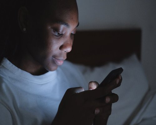 Person adjusting smartphone screen brightness in a dimly lit room